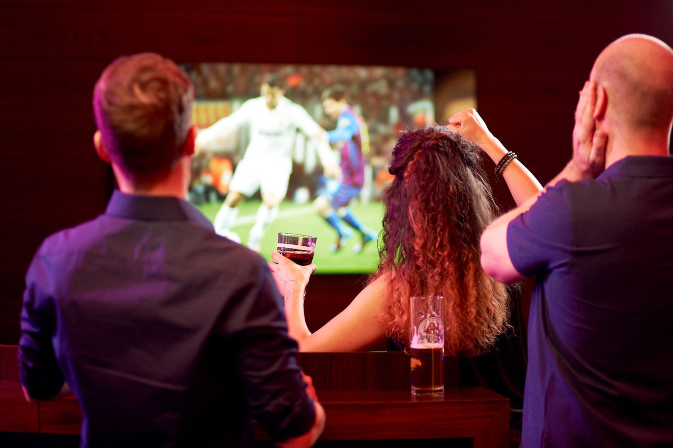 Zwei Männer und eine Frau schauen Fußball